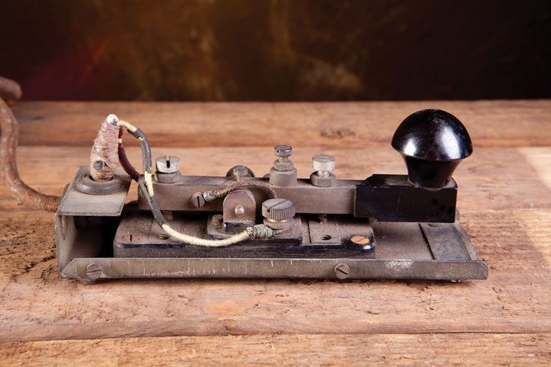 Oude morse-telegraaf met zwarte knop op een houten tafel